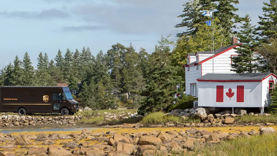a U P S truck approaching a house with the canadian flag